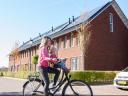 Vrouw fiets door wijk met zonnepanelen